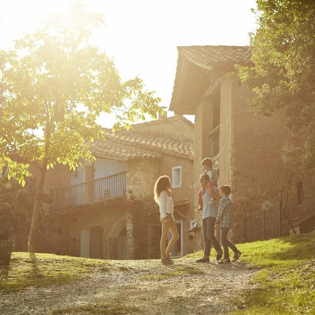 Full length of family standing on pathway against houses. Parents and children enjoying on sunny day. They are in casuals.