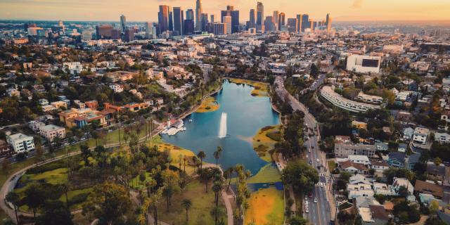 This is a drone photo taken from the above of the Echo Lake Park during sunset, showing the lake and the skyline of DTLA