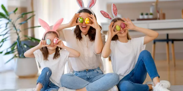 Buone vacanze. Madre e figlie con uova dipinte. Famiglia che festeggia la Pasqua. Le bambine indossano orecchie da coniglio.