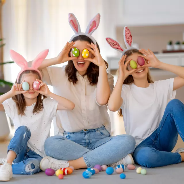 Buone vacanze. Madre e figlie con uova dipinte. Famiglia che festeggia la Pasqua. Le bambine indossano orecchie da coniglio.