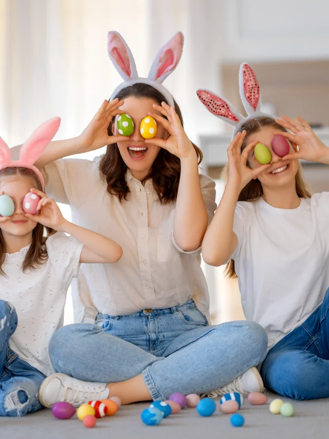 Ein glücklicher Feiertag. Mutter und ihre Töchter mit bemalten Eiern. Familie feiert Ostern. Cute little children girls are wearing bunny ears.