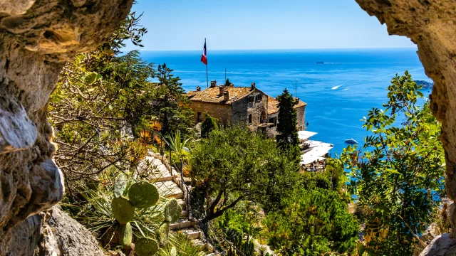 Eze, France - August 1, 2022: Chateau Eza hotel on slope of medieval fortress castle hill on top of historic town of Eze at French Riviera Coast of Mediterranean Sea