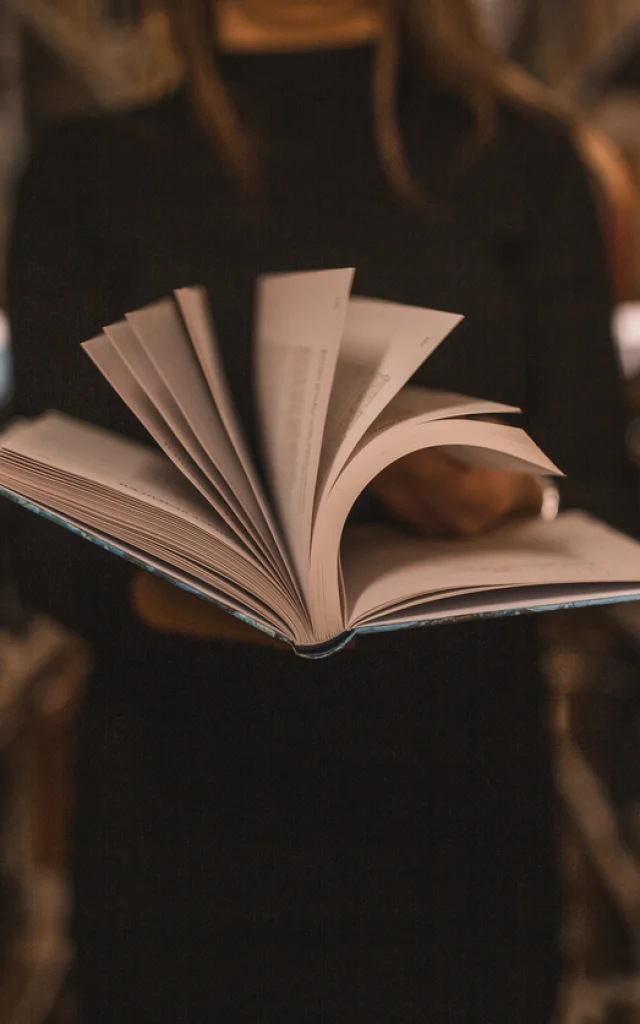 An unrecognizable librarian holds a book in her hands and turns the pages