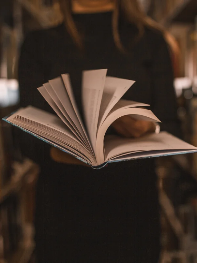 An unrecognizable librarian holds a book in her hands and turns the pages